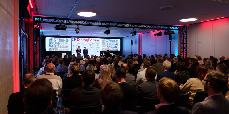 Bild des 1. CorFactum Dialogforums vom Publikum auf die Bühne